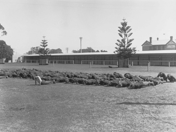 Image: group of men in uniforms doing push-ups on oval